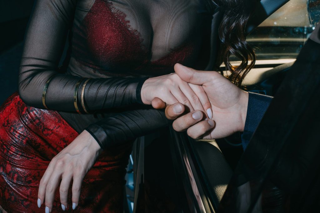 cropped view of man in car and woman holding hands